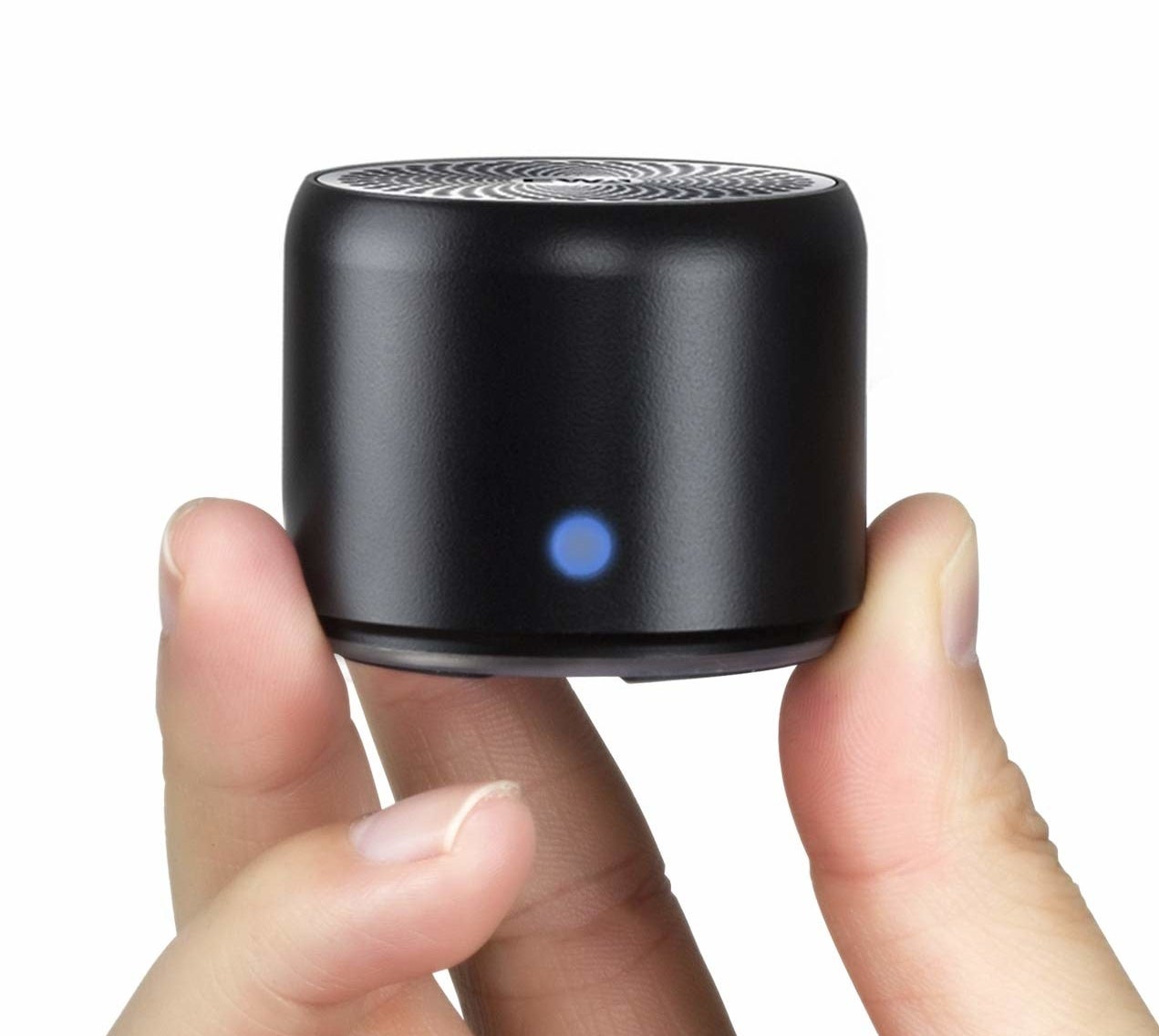 A person holding the small cylindrical speaker between their fingers
