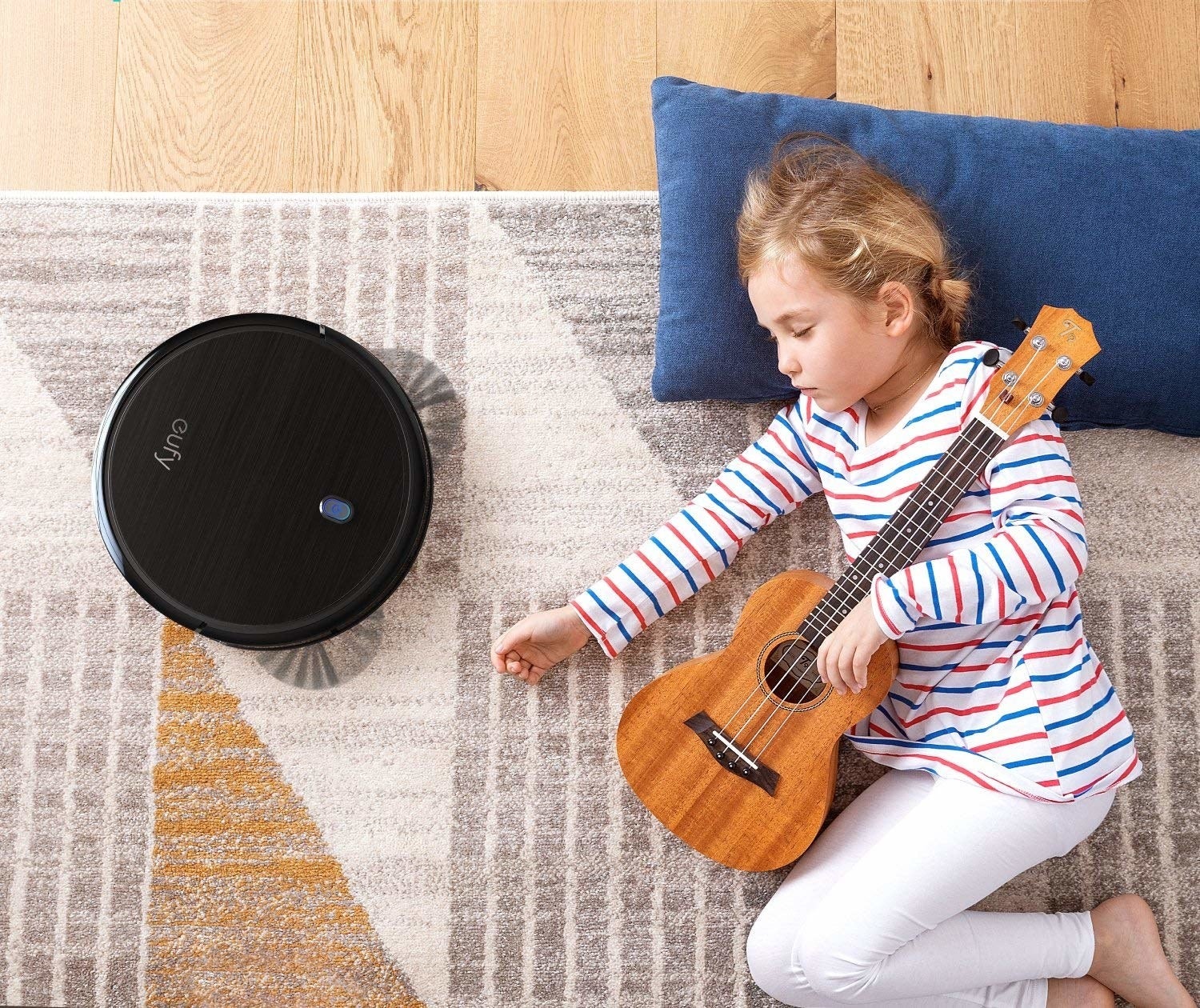 A child sleeping on the floor as the robot vacuum is running