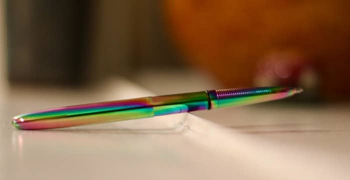 The metal and rainbow-colored pen displayed on a table