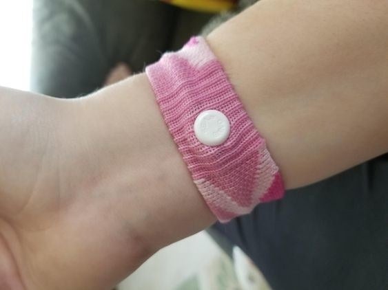 reviewer wearing the anti-nausea wristband in pink 