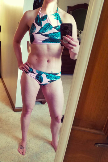 reviewer wearing the pink and green leaf print halter bikini