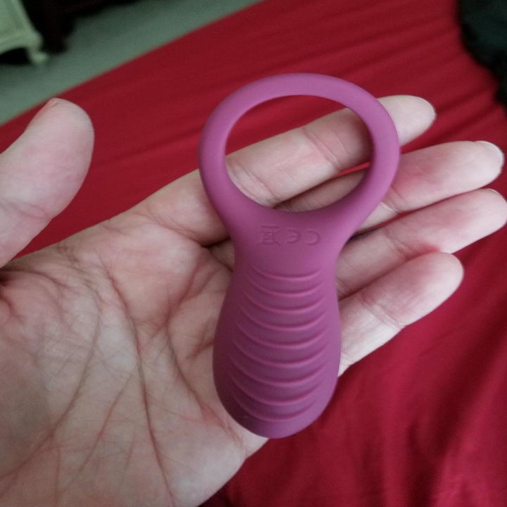 A reviewer holding the ring. It has a wide silicone ring and a thick, ridged, lightweight vibrating base