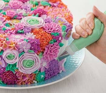 A person decorating a cake with one of the tips from the kit