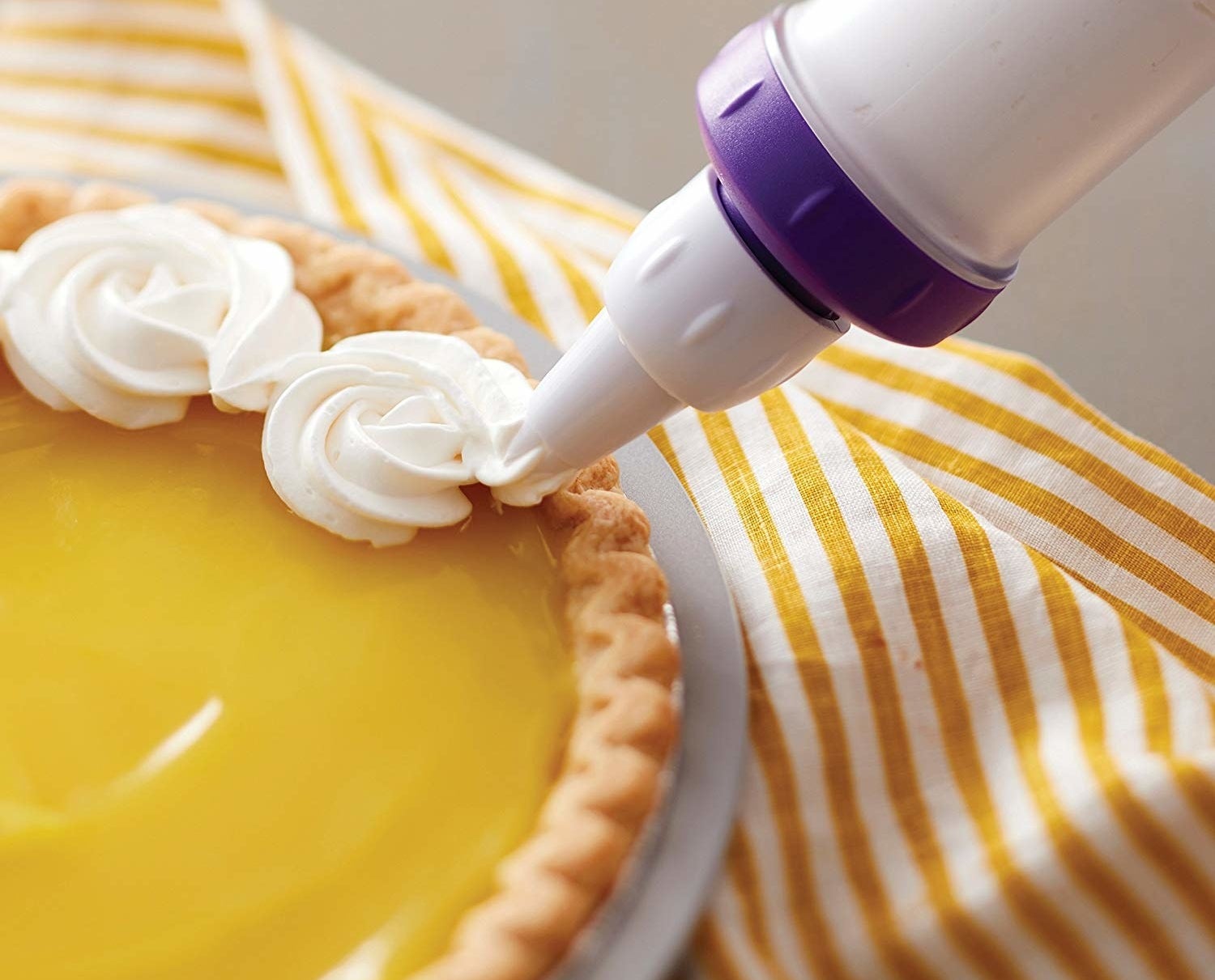 The decorating tool creating small, rose-like puffs of cream on a pie