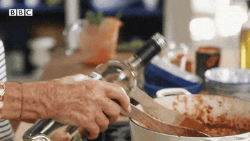 Mary Berry pouring wine in a pot of cooking sauce