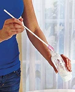 person using the long spatula to get into a toiletry bottle