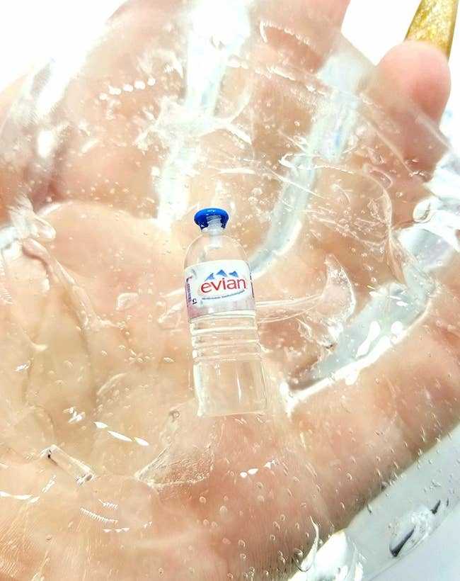 hand holds slime with plastic mini evian bottle in it 