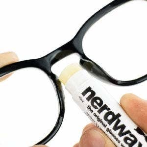 rubbing the lip balm-like tube onto nose bridge of glasses