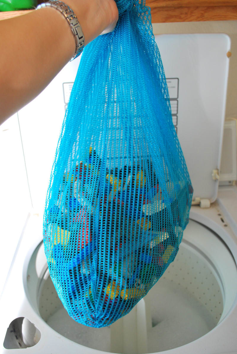 Hand holding a mesh bag filled with Legos over an open washer