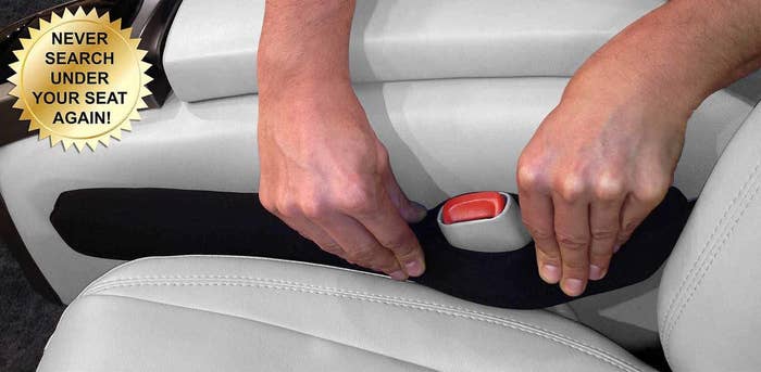 person pressing the black seat gap filler around a seat belt buckle between the car console and seat