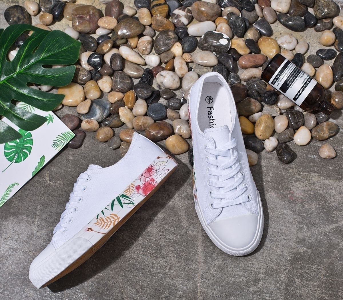 A classic white sneaker with a floral pattern on the sides of the rubber soles 