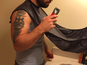reviewer pic of person with a beard using the bib and holding a trimmer