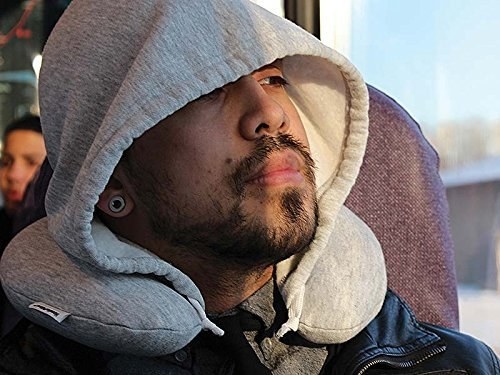 person on a large bus wearing the pillow that&#x27;s a neck travel pillow with a hoodie attached to it