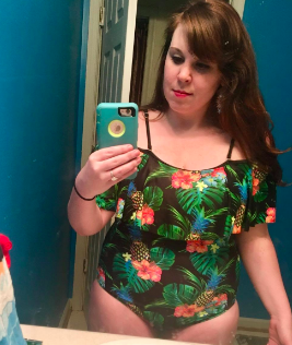 a reviewer wearing the bathing suit in black with tropical flower son it