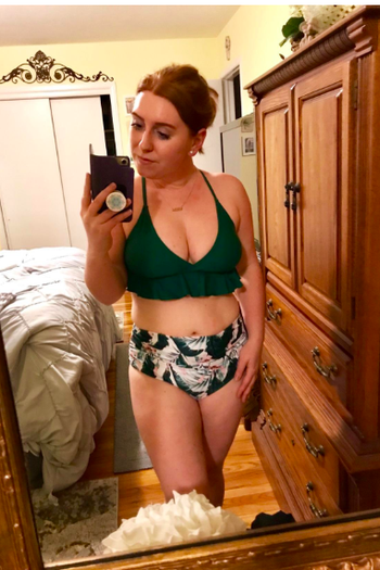 reviewer wearing the peplum top bikini with a green top and tropical print high-waisted bottoms