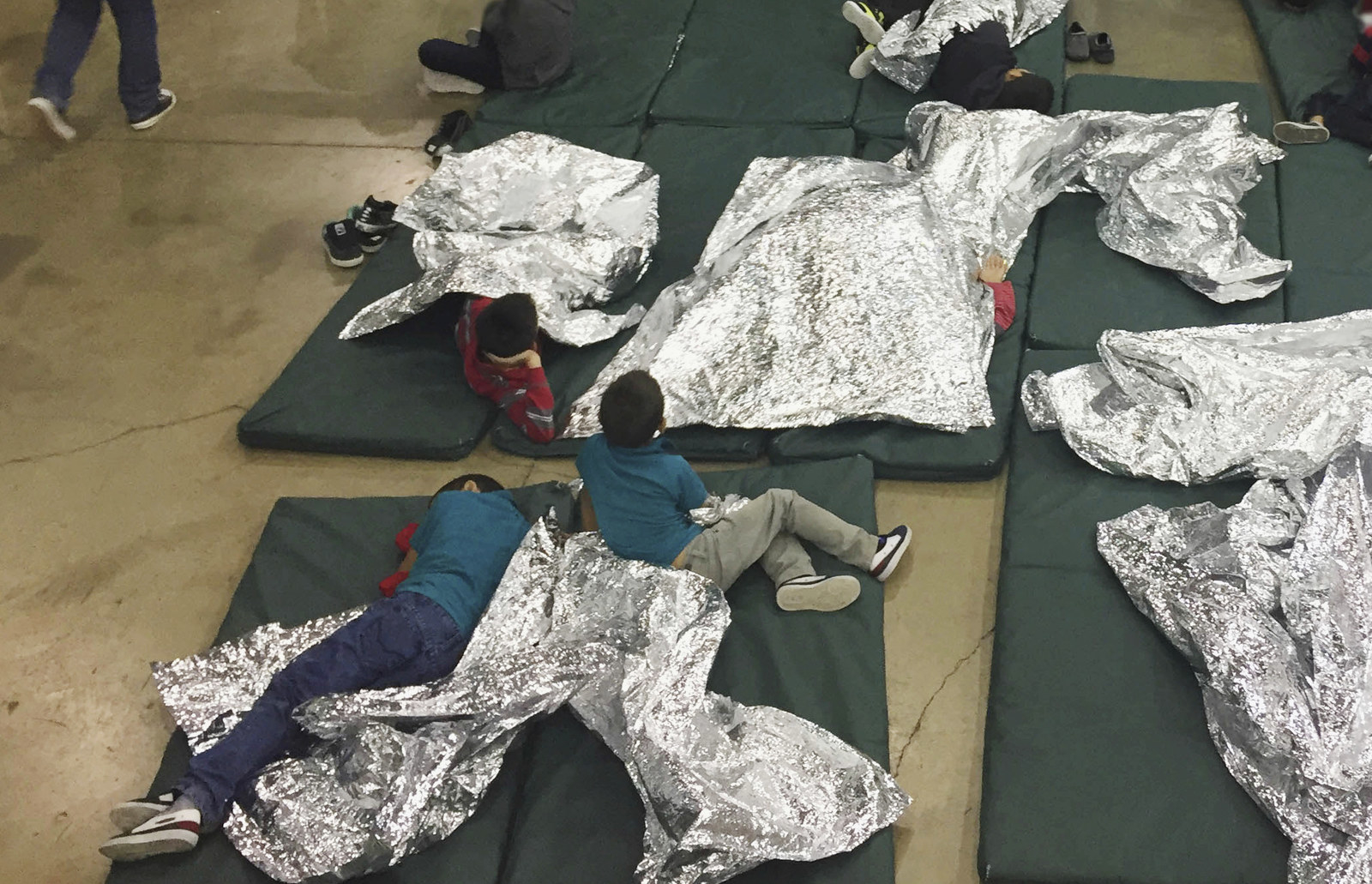 In this June 17, 2018, file photo, people, including children, who have been taken into custody related to cases of unauthorized entry into the United States rest in cages at a facility in McAllen, Texas.