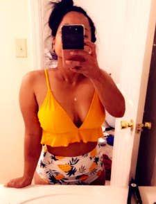 a reviewer wearing the yellow bathing suit top with a ruffled hem and the pineapple print bottoms