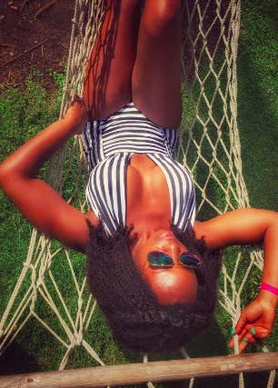 a reviewer laying in a hammock int he one piece with a deep v-neck and a vertical black and white stripe pattern