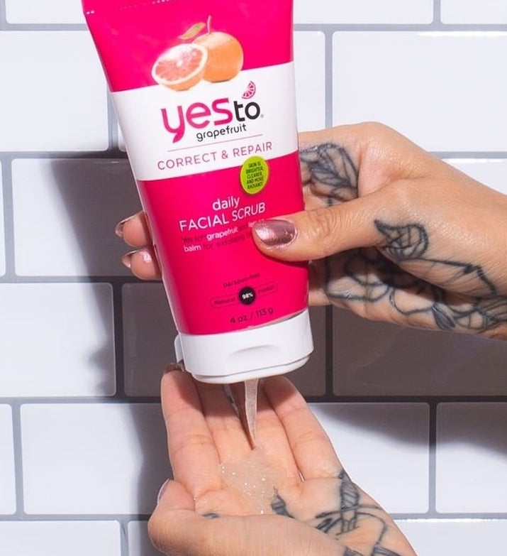 handle squeezing product out of white and pink bottle labeled &quot;yes to grapefruit correct &amp;amp; repair daily facial scrub&quot; 