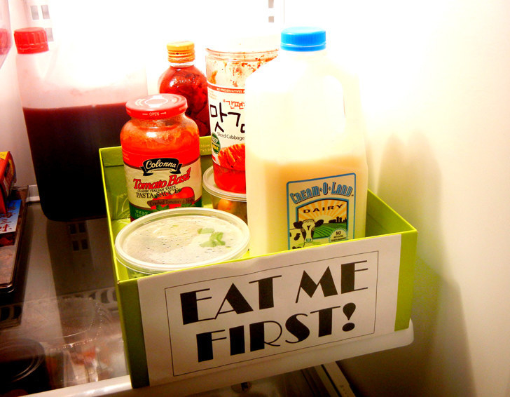 shoebox with &quot;eat me first&quot; sign on the front, sitting in fridge filled with various products
