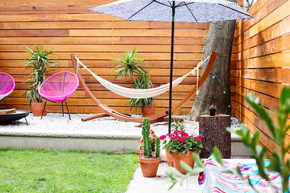 backyard with hammock and umbrella and container plants in it