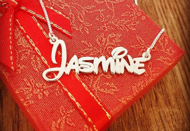 a gold necklace that says "jasmine" in Disney script