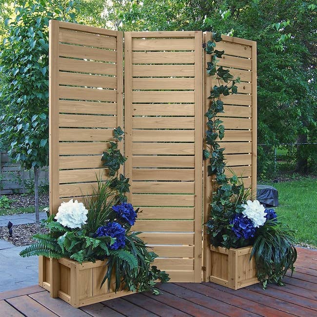 three panel wood privacy screen with planters for flowers at the bottom 