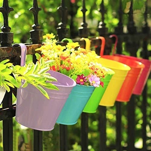 a row of colorful buckets with plants in them