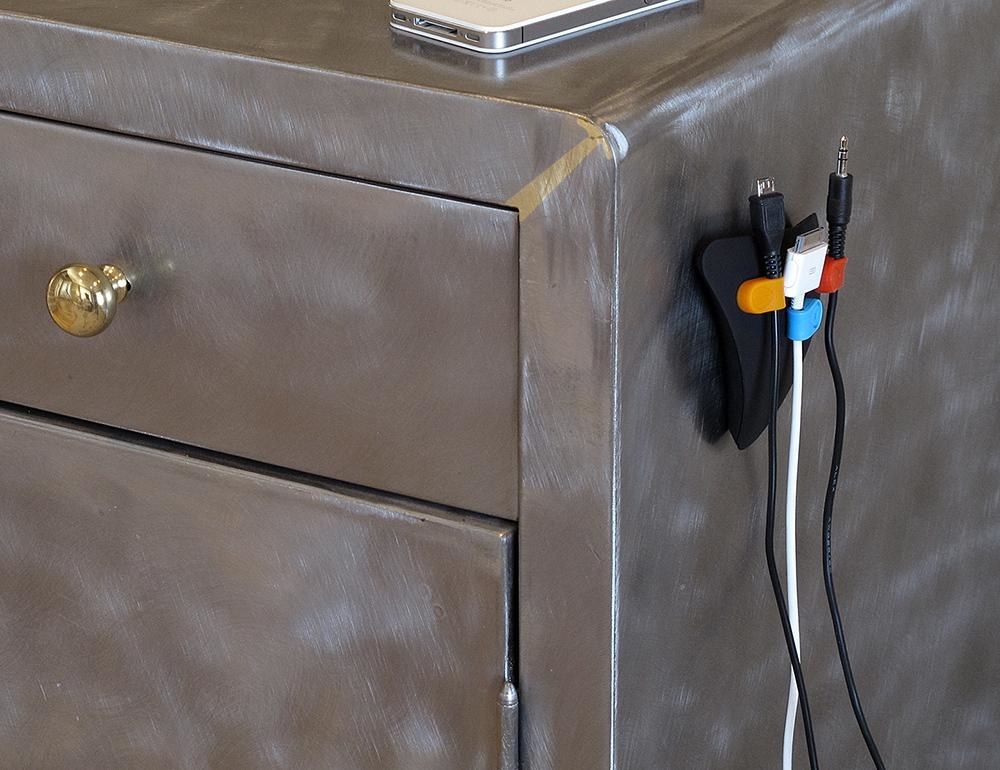 The magnetic cord organizer attached to the side of a nightstand. 