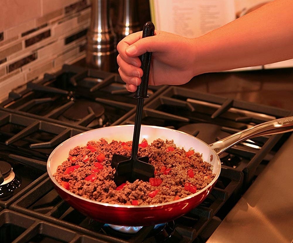 A person breaking down ground meat with the chopper. 