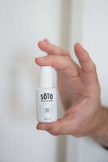 A person holding up a bottle of the touch up paint