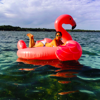 A reviewer lying on her stomach on the flamingo in body of water