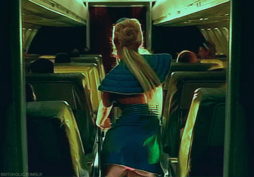 Britney Spears pushing a cart down the aisle in an airplane while dancing sexually