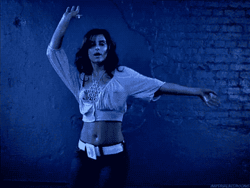 Nelly Furtado shaking her butt as she dances in front of a brick wall