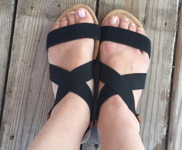a reviewer&#x27;s feet in the black strappy sandals