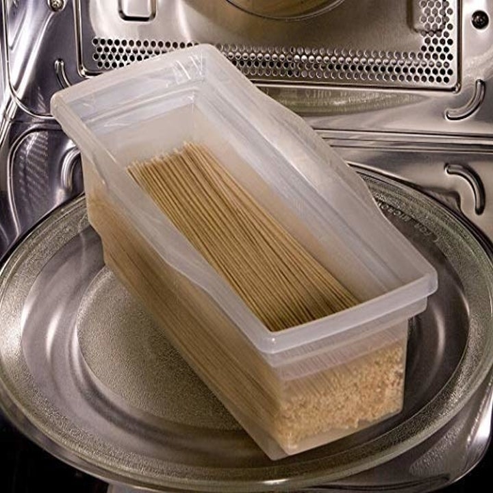 The pasta cooker filled with pasta and water in a microwave
