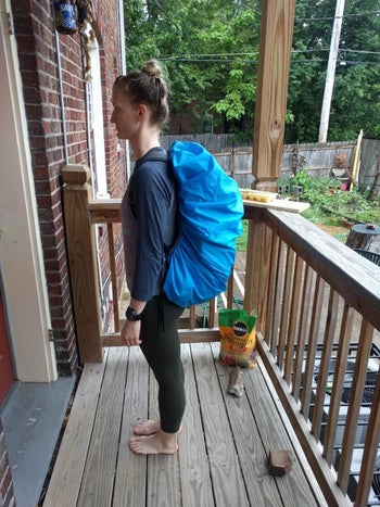 reviewer photo of them showing how the cover wears over their large hiking backpack, side