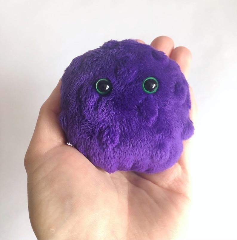 a hand holding onto the fuzzy worry pet which has googly eyes