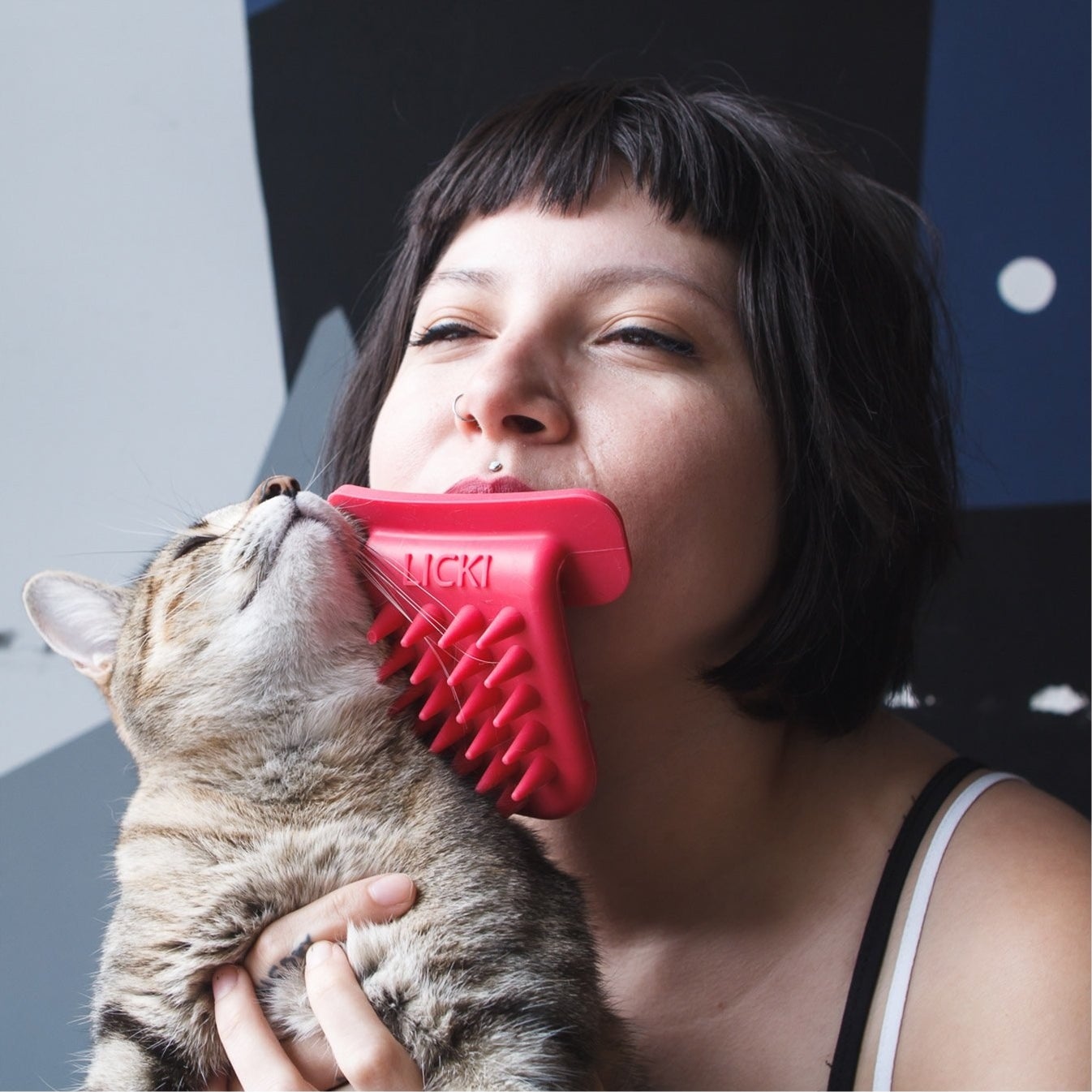 model licks cat with tongue shaped device with bristles on it 