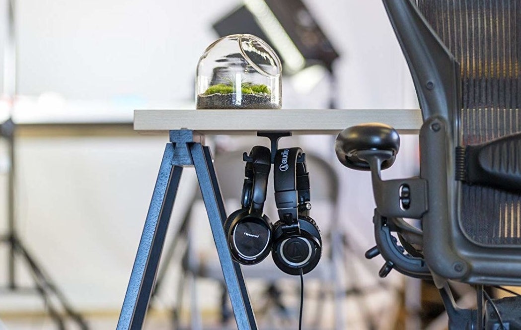 the under-desk mount holding two pairs of headphones