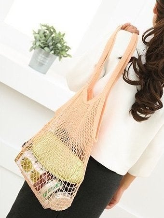 model holding a peach mesh string bag