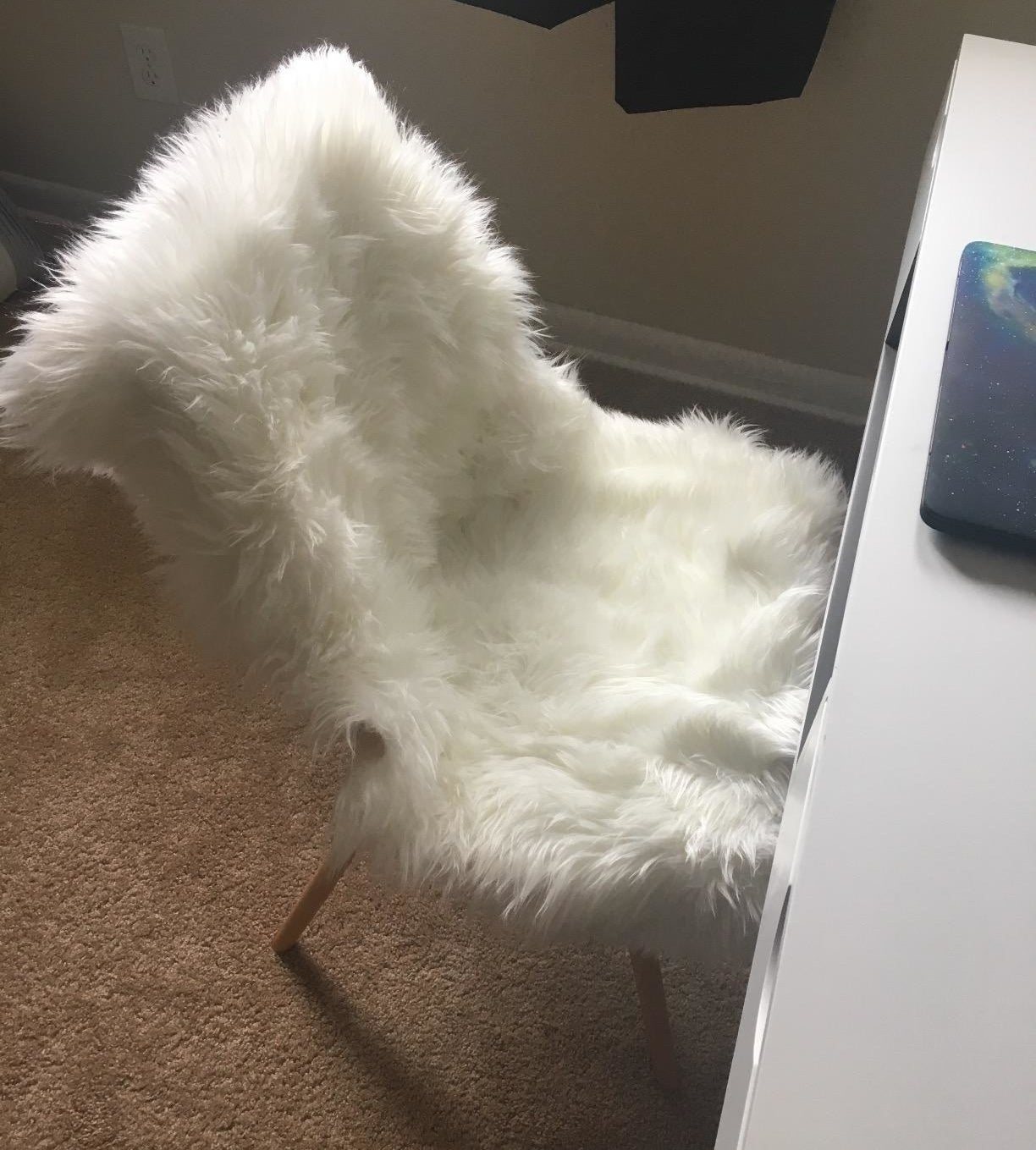 a reviewer&#x27;s image of the faux fur rug draped over a desk chair