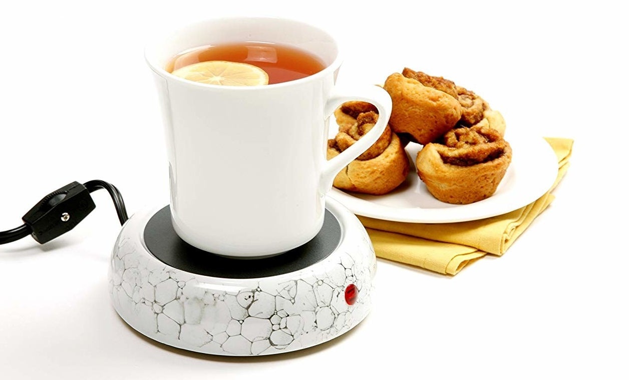 a mug on the mug warmer next to a small plate of pastries