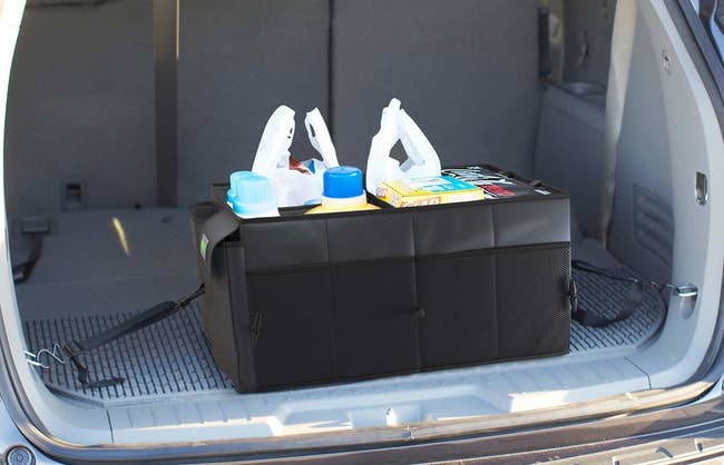 The organizer in the trunk of a minivan, with straps securing it to either side; it fits multiple grocery bags worth of things