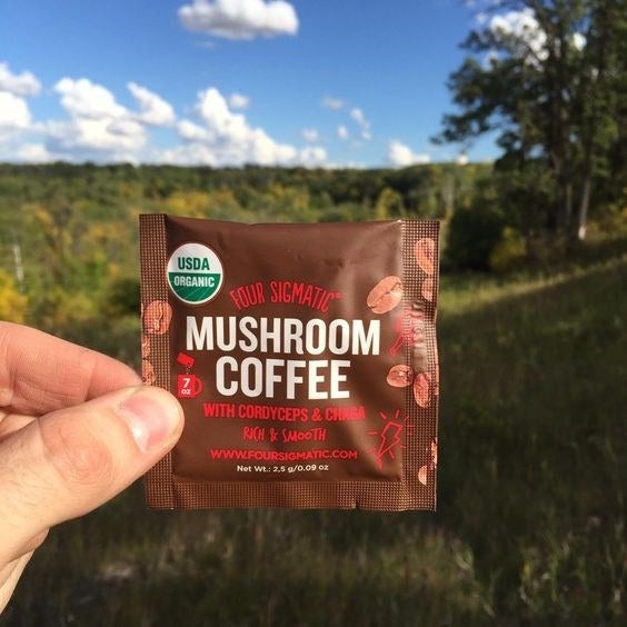 Reviewer holding up a packet of the mushroom coffee mix