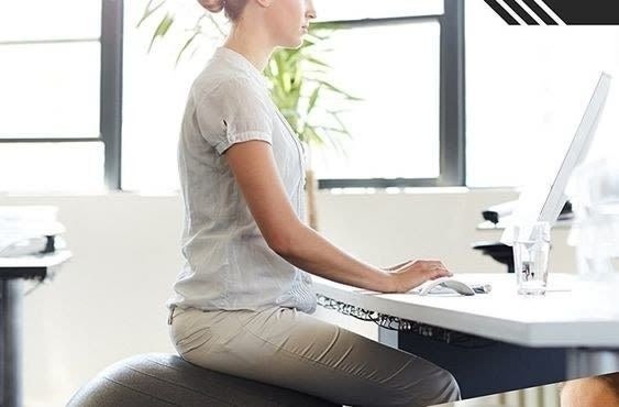 Model working at a desk while sitting on the ball