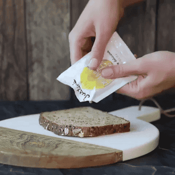 Gif of the honey peanut butter being squeezed out of its packaging onto a piece of bread
