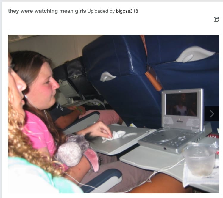 A photo of two tween girls (one holding an Eeyore stuffed animal) sitting in plane, sharing a headphone and watching Mean Girls of a portable DVD player.