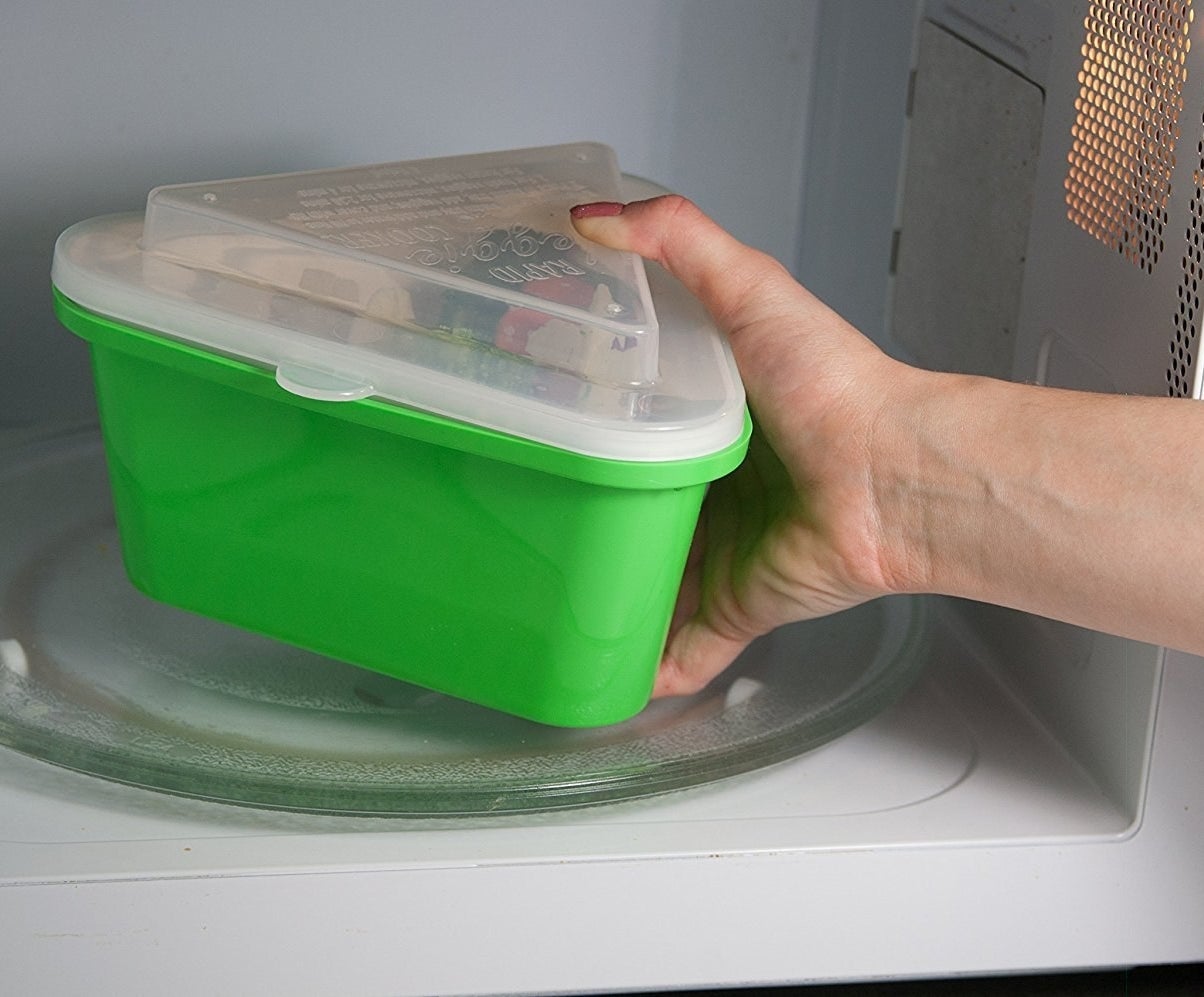 A model placing a green triangular steamer into a microwave 