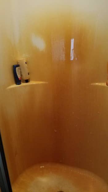 Reviewer photo showing a shower covered in orange rust stains